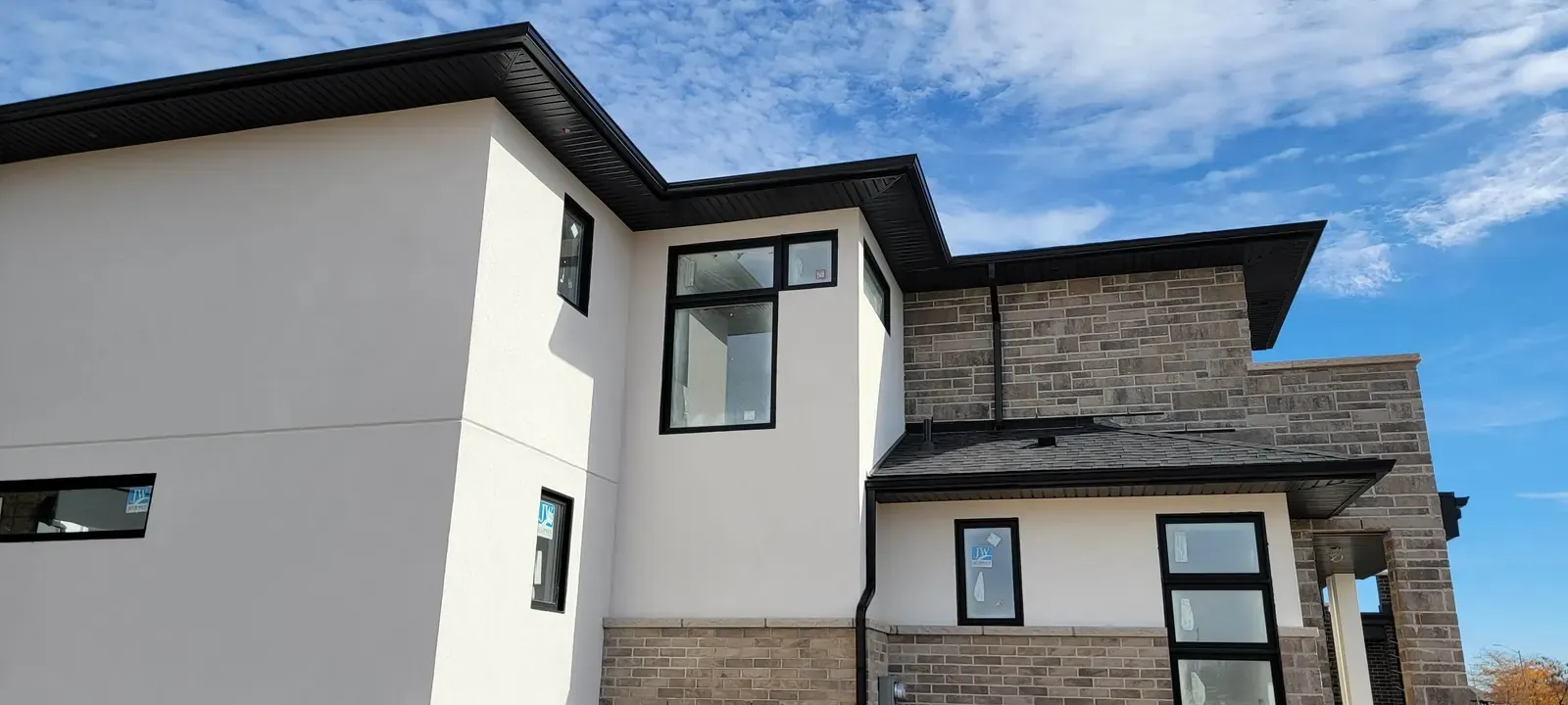 Modern stucco residence with stone transitions and dark windows