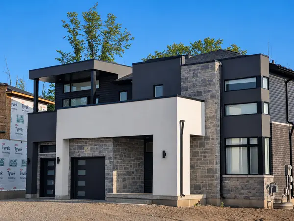 Modern two-storey home with white stucco, stone and dark accents