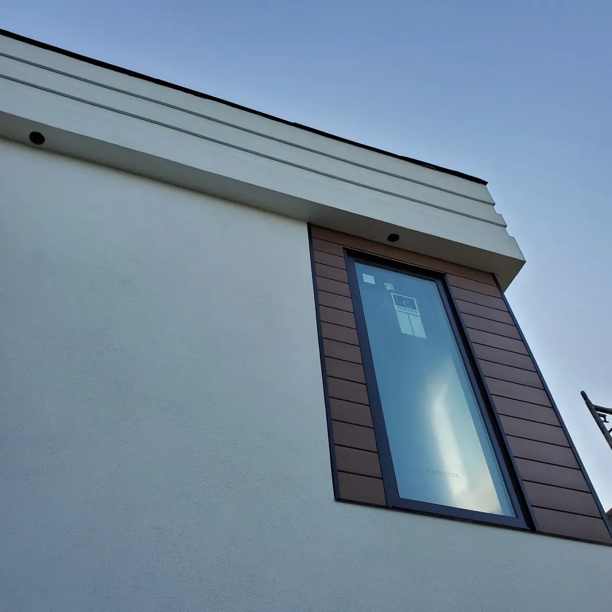 Smooth stucco wall with a recessed window and wood-tone trim